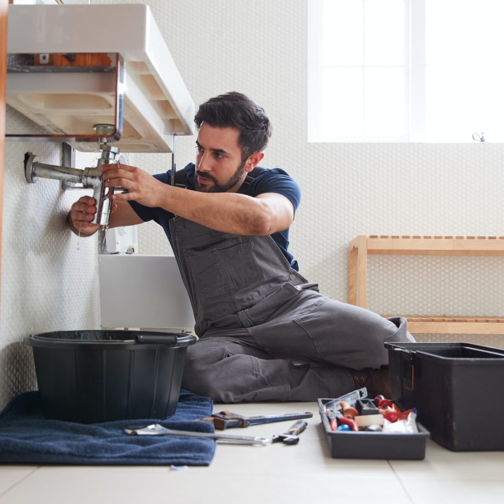 male-plumber-working-to-fix-leaking-sink-in-home-bathroom.jpg